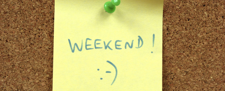 Yellow small sticky note on an office cork bulletin board. Weekend happiness.